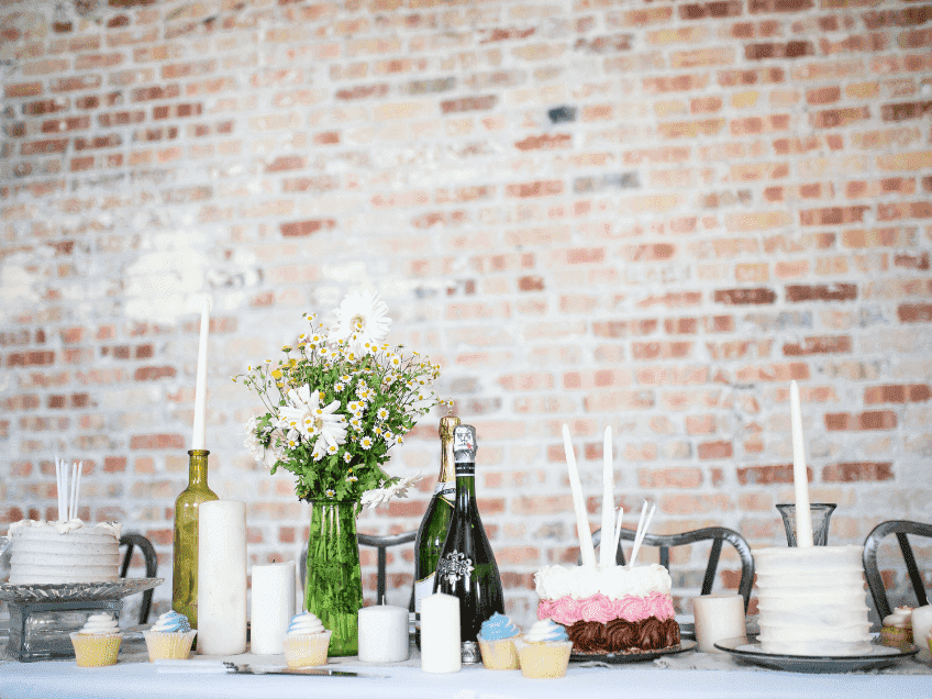 Backsteinwand mit schönem Kuchentisch zur Urban Chic Wedding (c) Brooke Lark